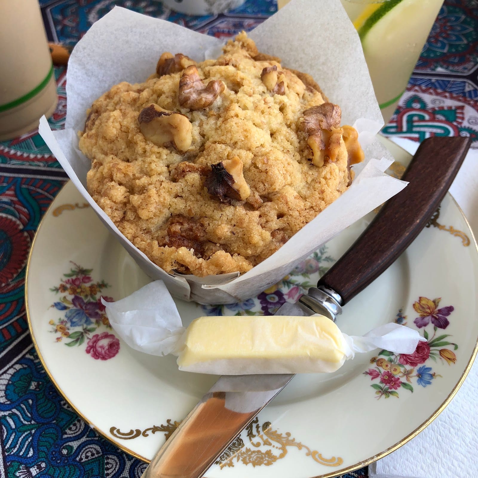 A walnut-topped bake with butter on a floral plate.