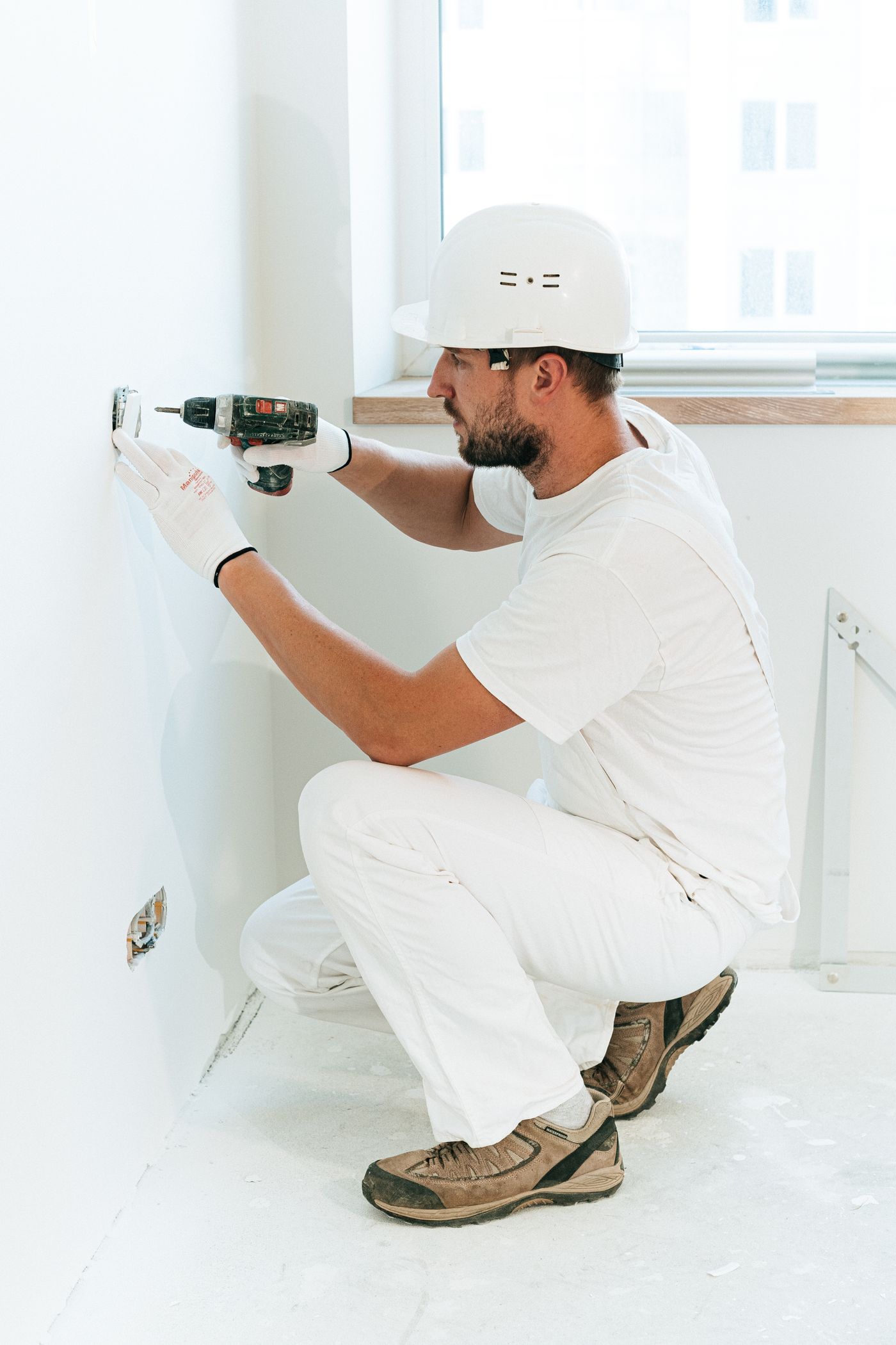 Worker fitting a wall outlet with a cordless drill