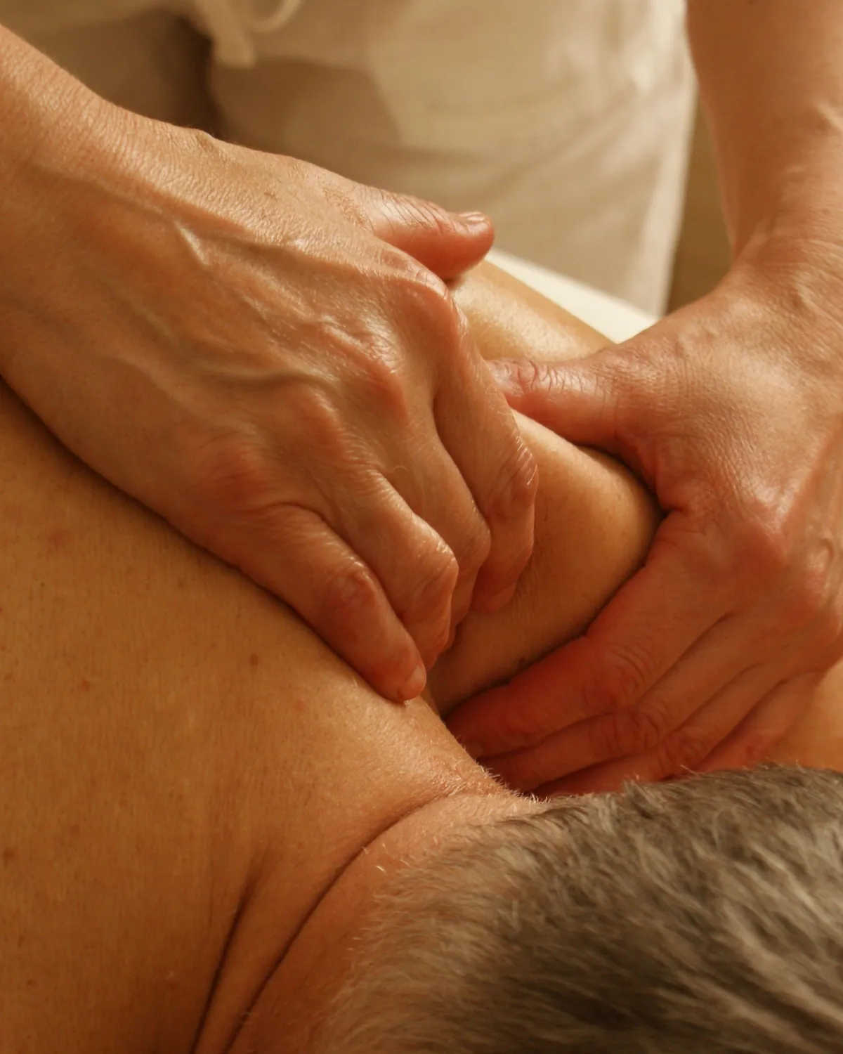 Two hands pressing into the top of a client's shoulder.
