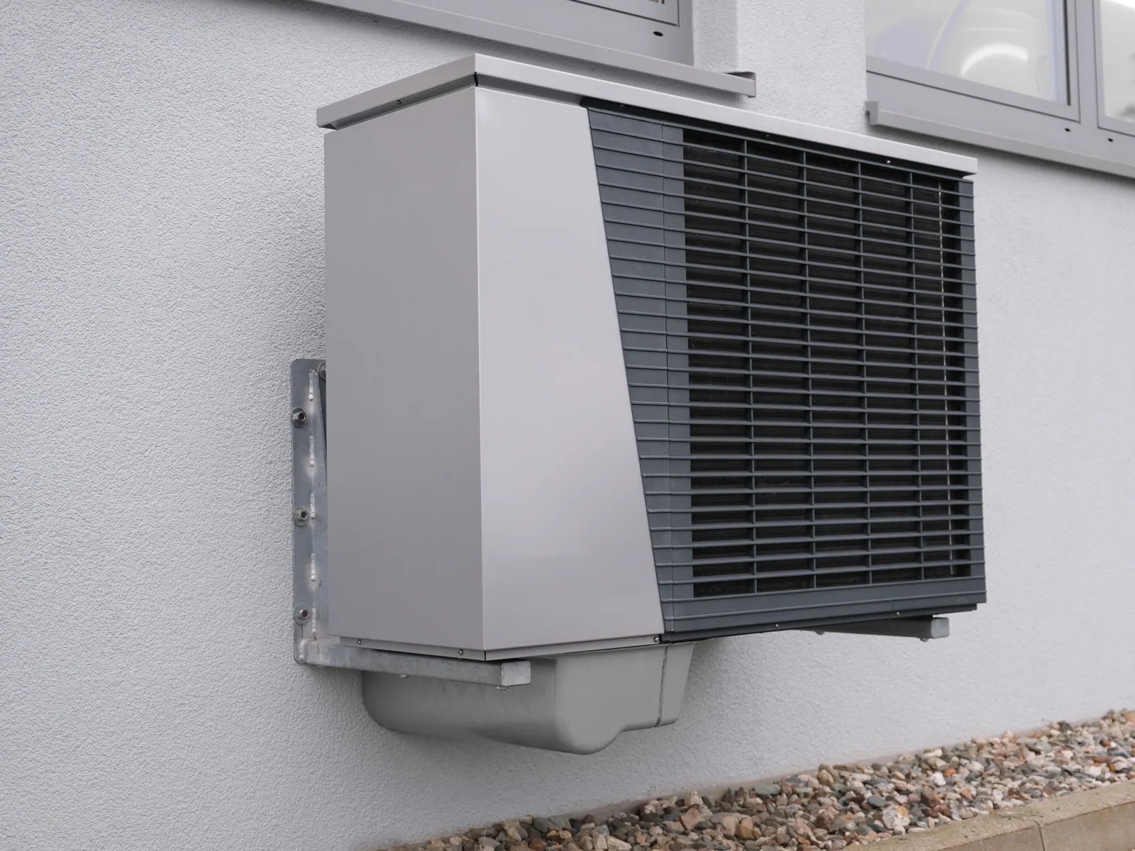 Outdoor heat pump unit mounted on a rendered wall