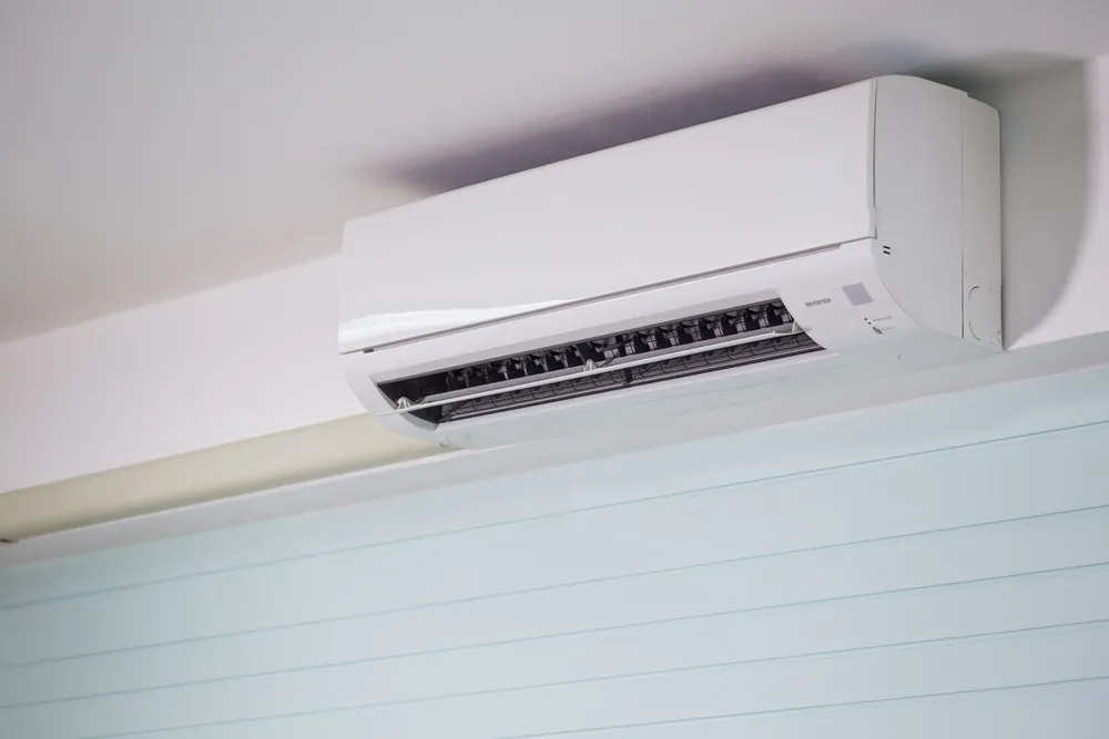 Close-up of a white wall-mounted heat pump with its air vents open