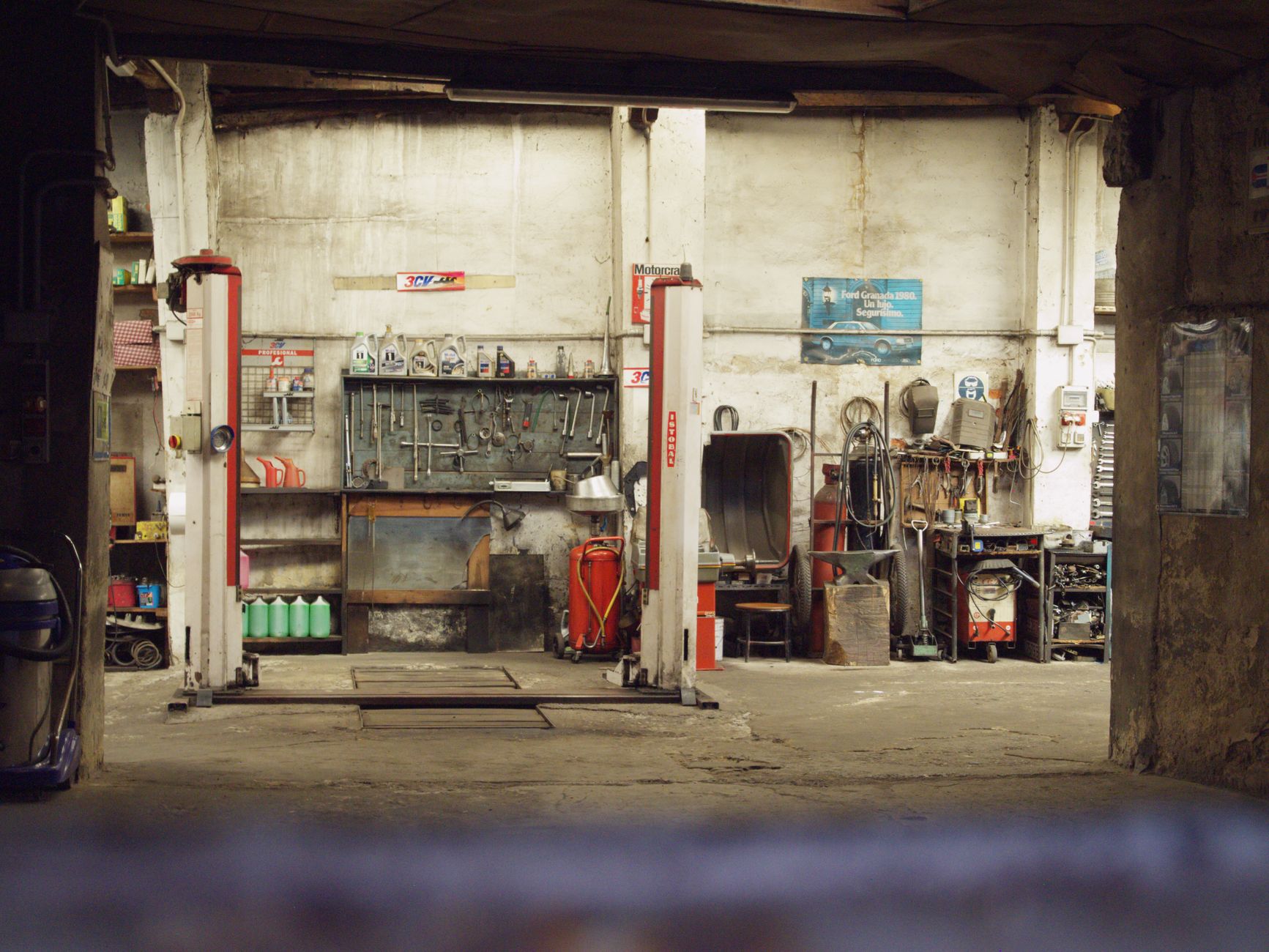Empty car workshop bay with a two-post lift and tools on the wall
