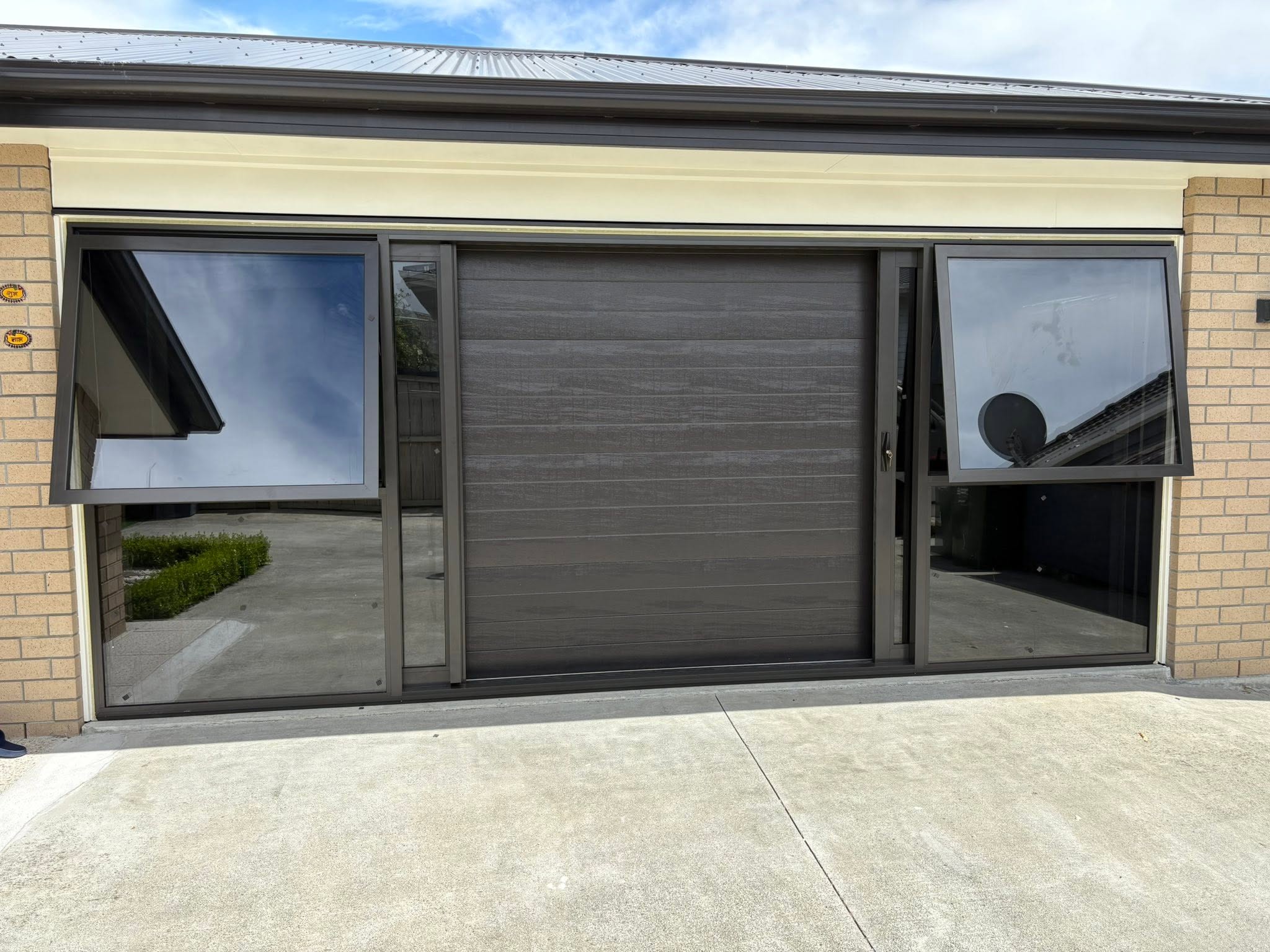 Dark aluminium sliding door with frosted glass at a modern house entrance