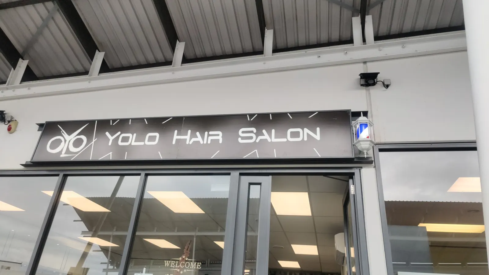 The Yolo Hair Salon shopfront, with its name on a dark sign above the windows.