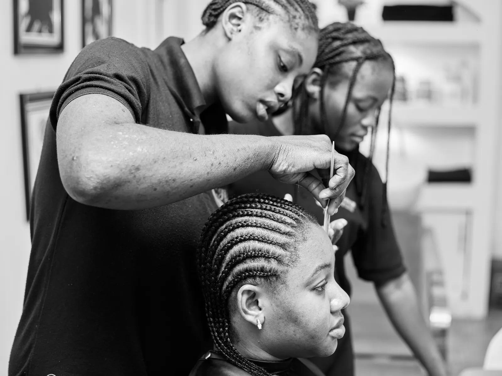 A stylist braiding a client’s hair into neat rows.