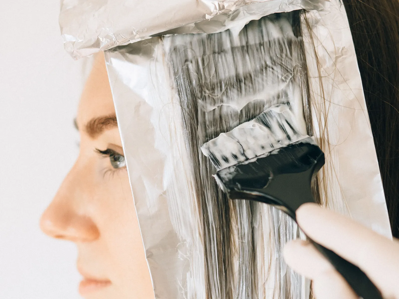 A brush painting colour onto a section of hair laid over foil.