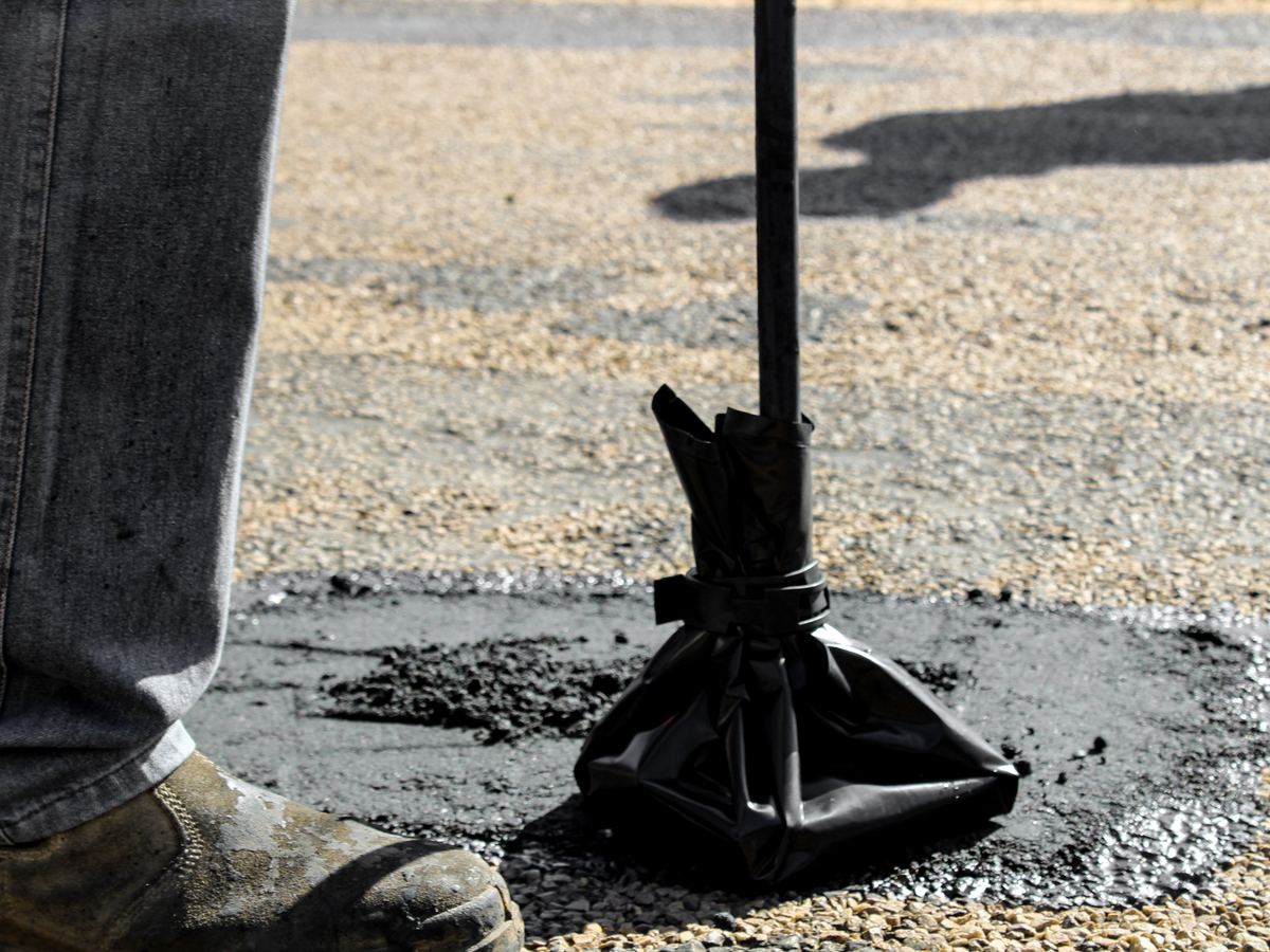 Fresh asphalt being worked into a damaged road surface
