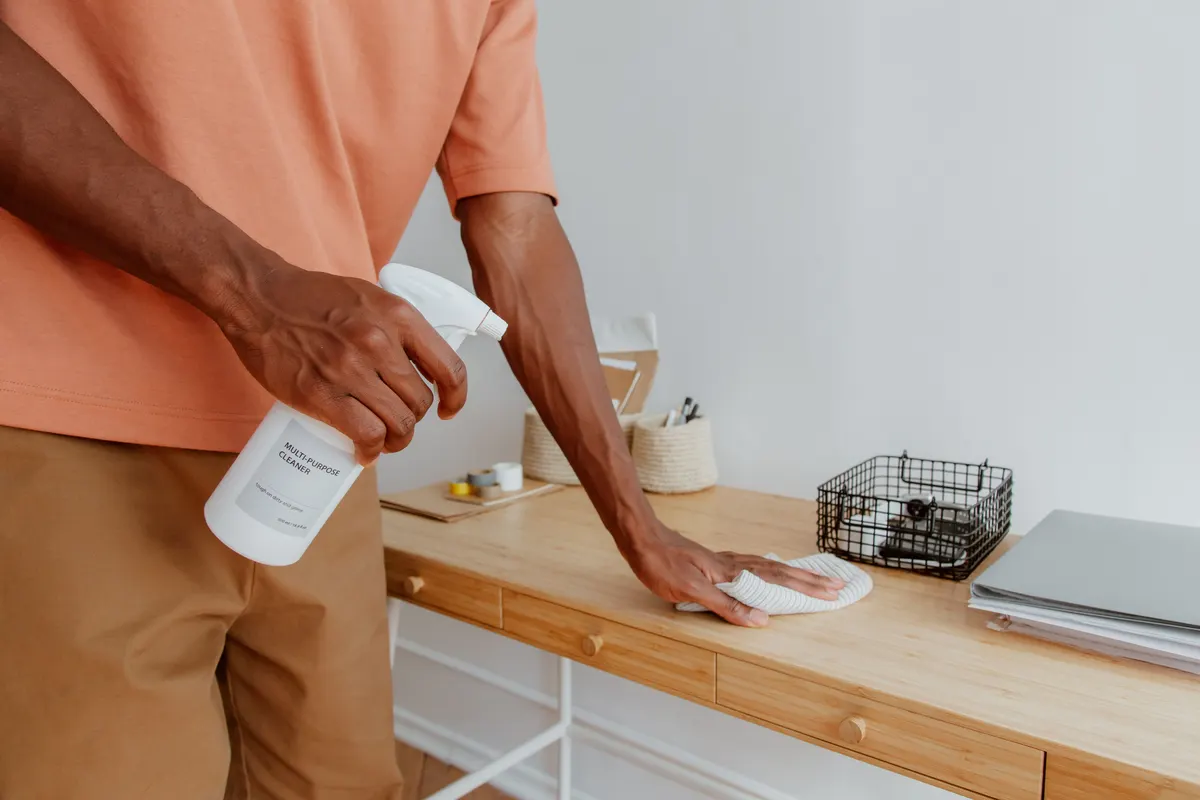 A person wiping down an office desk.