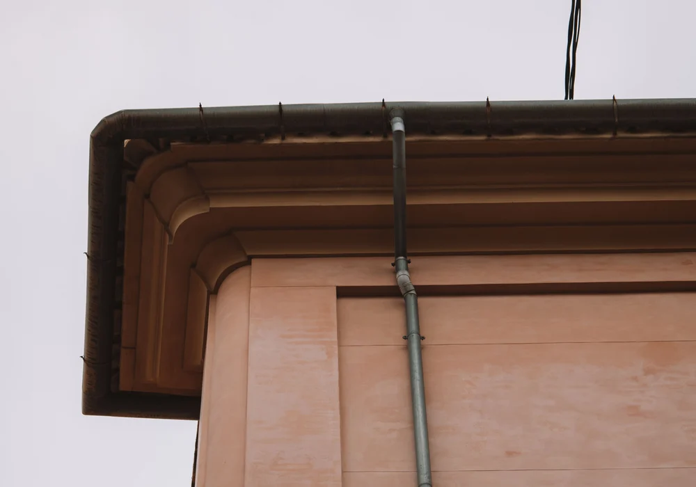 A residential roof edge with a gutter and downpipe