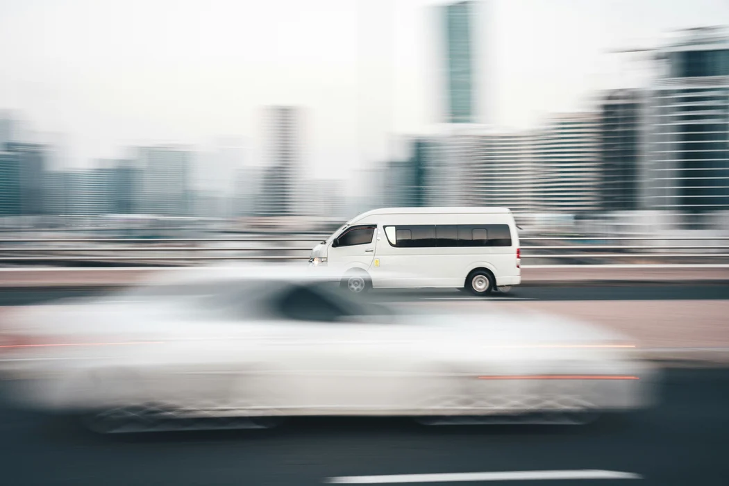 White van driving past city towers