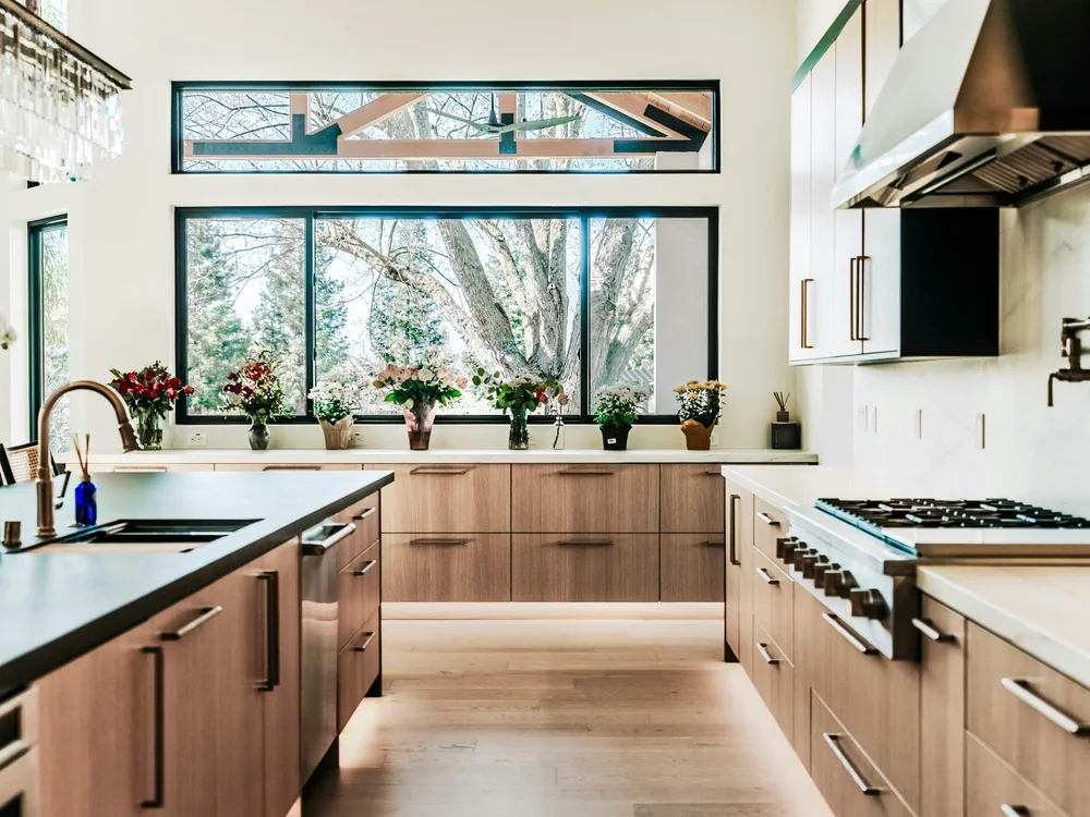 Wood kitchen cabinets beside a large dark-framed window.