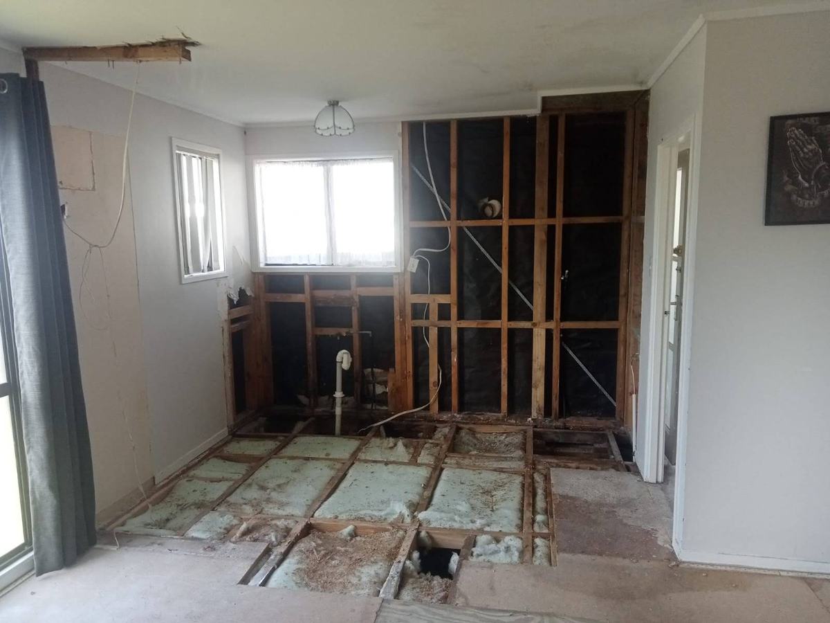 Room interior with an opened wall and exposed timber framing during renovation work.