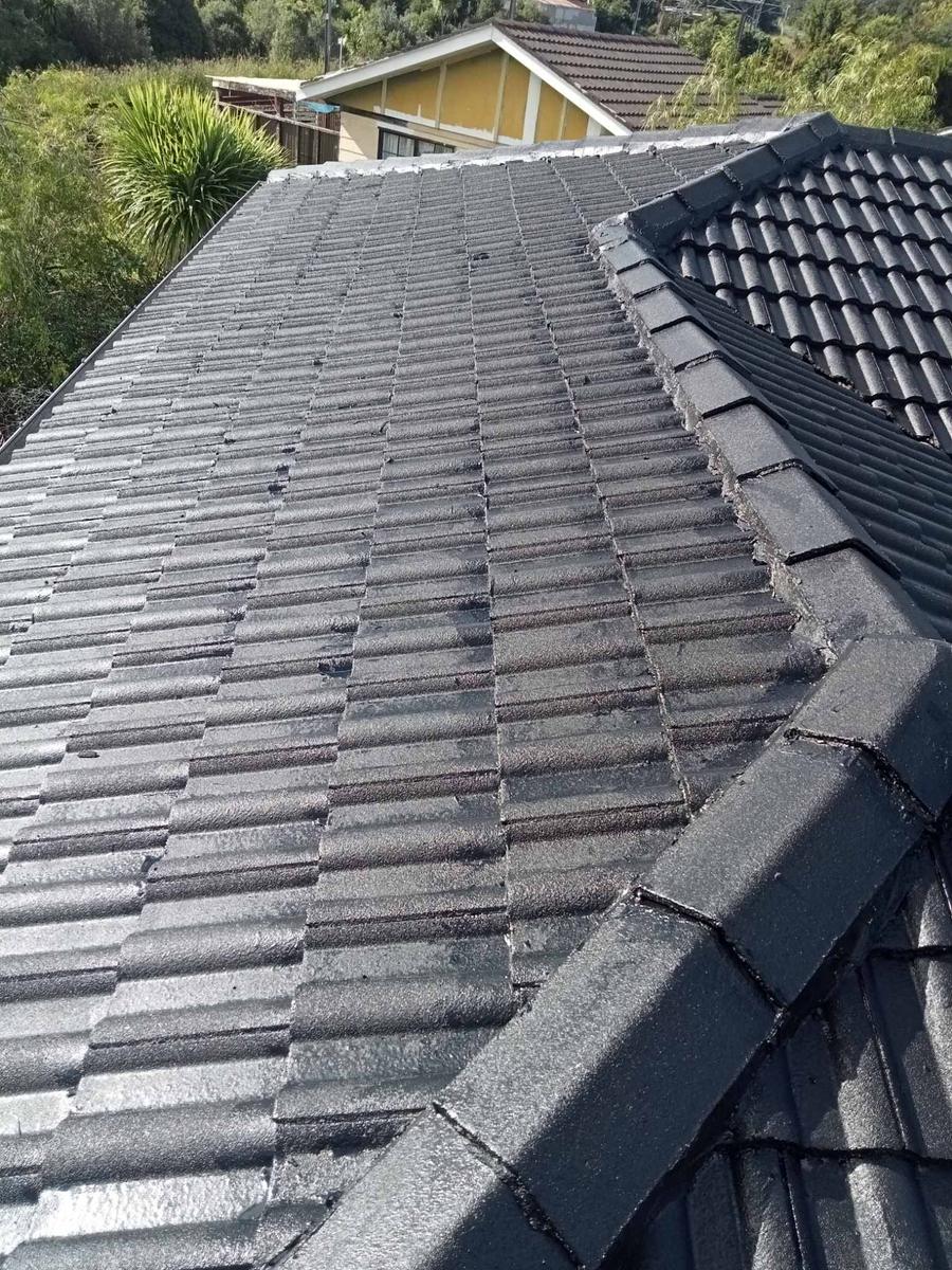 Close view of dark roof tiles and ridge capping on a house roof.