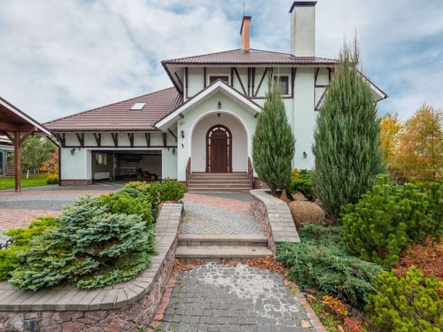A house exterior and paved driveway after cleaning, framed by planting.