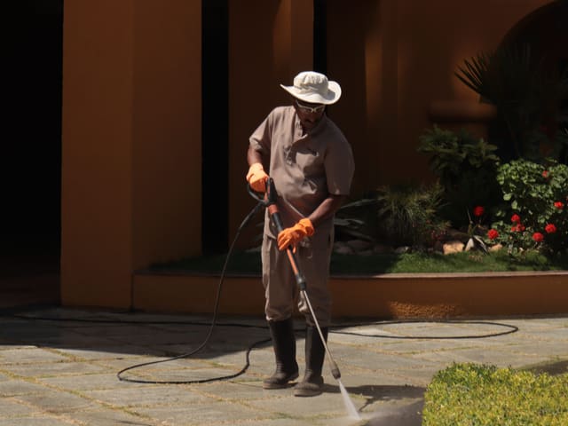 Paved courtyard being pressure washed, water running across the surface.