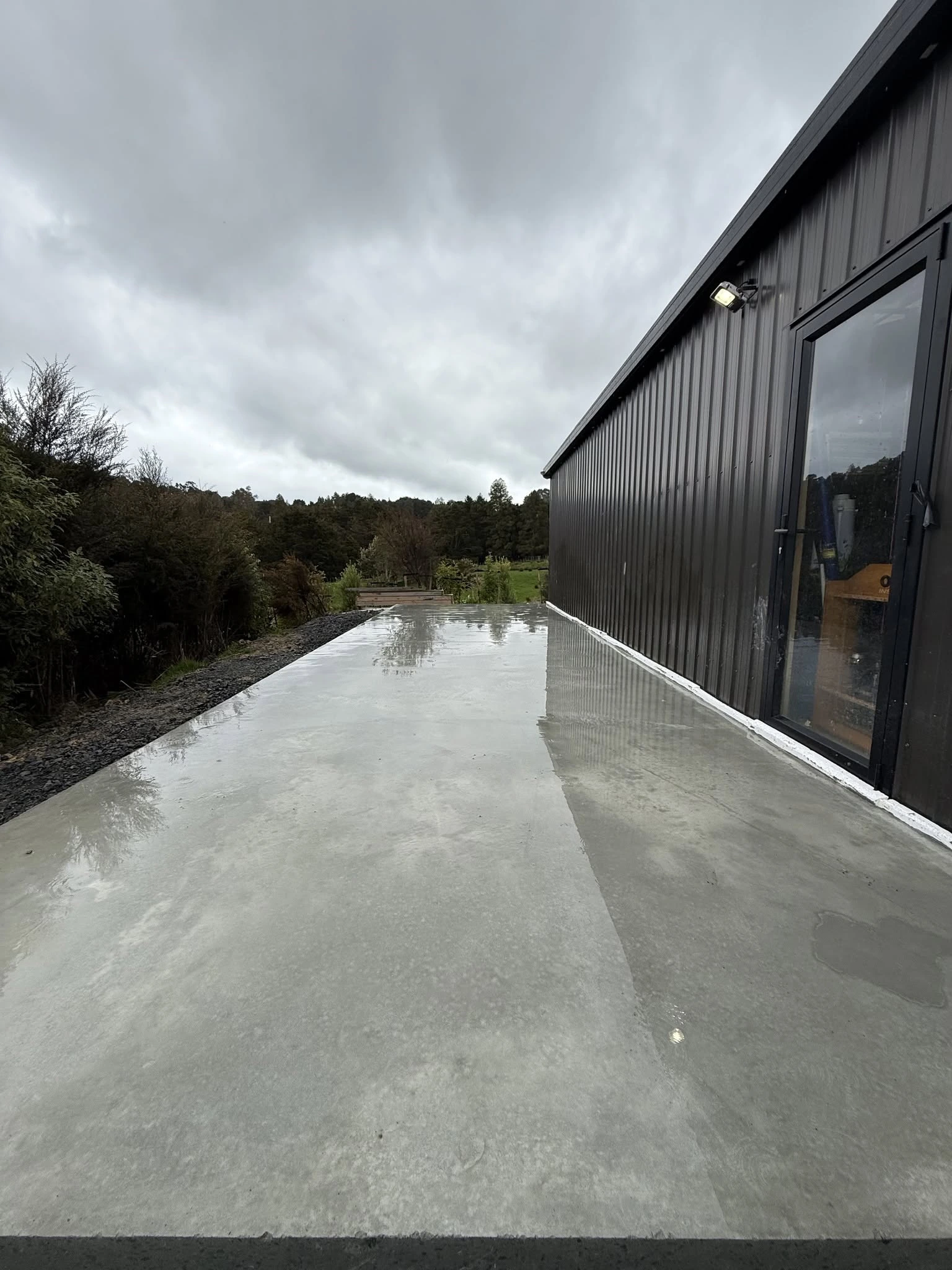 Long concrete slab and path beside a black-clad building