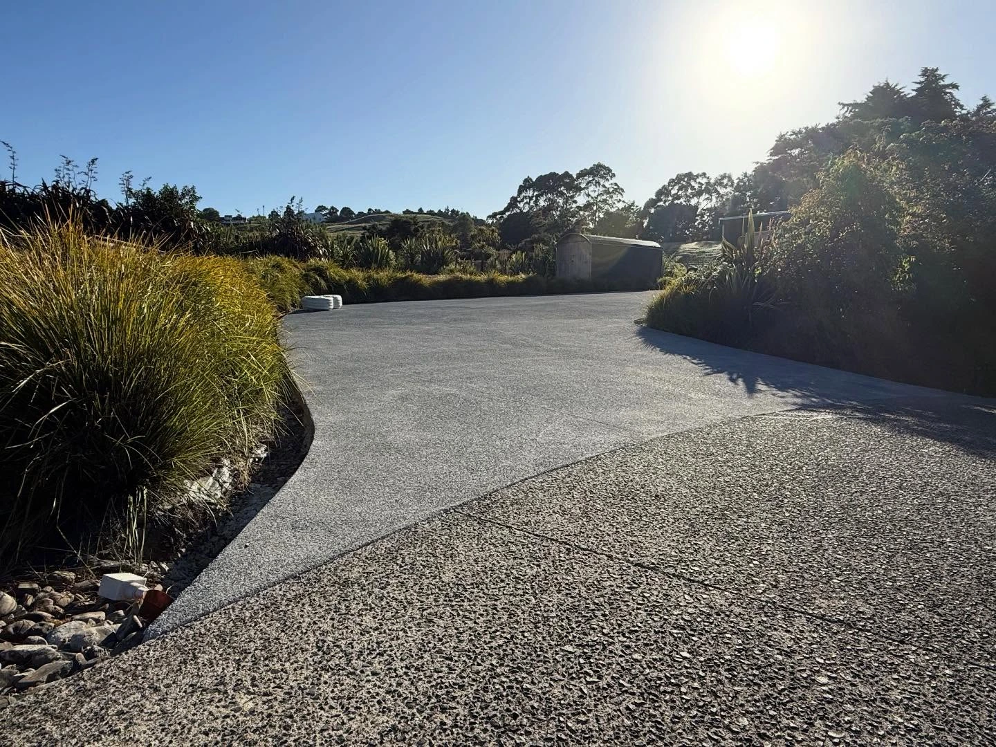 Curved exposed aggregate driveway through garden planting