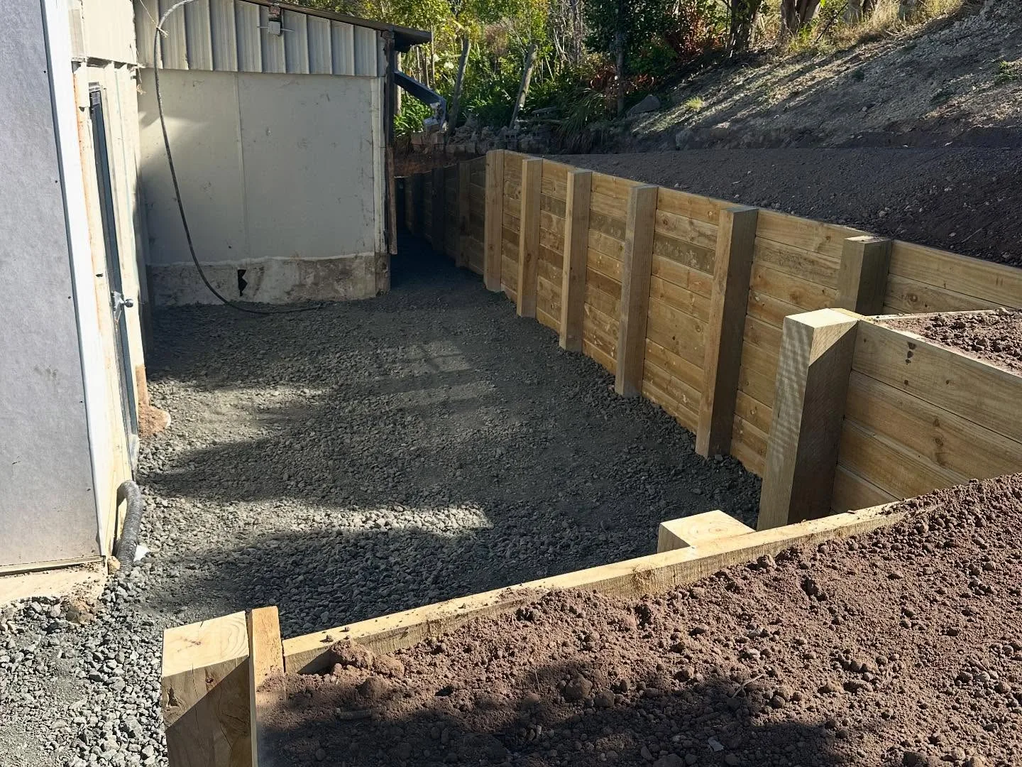 Close-up of timber posts and gravel along a retaining wall