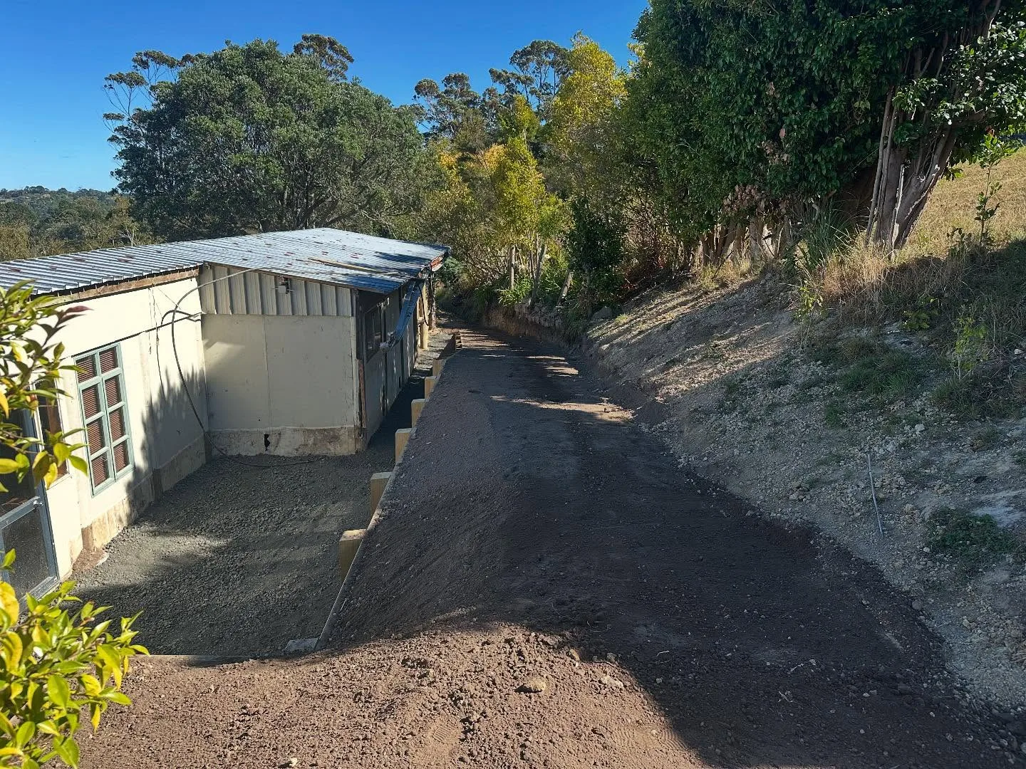 Finished timber retaining wall and concrete slab beside a garage