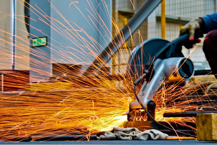 A cut-off saw throws orange sparks while slicing through a metal workpiece