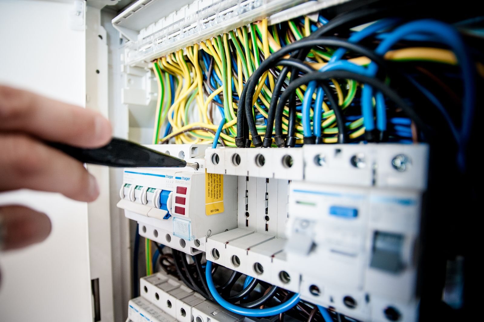 Electrician testing an open switchboard with a multimeter