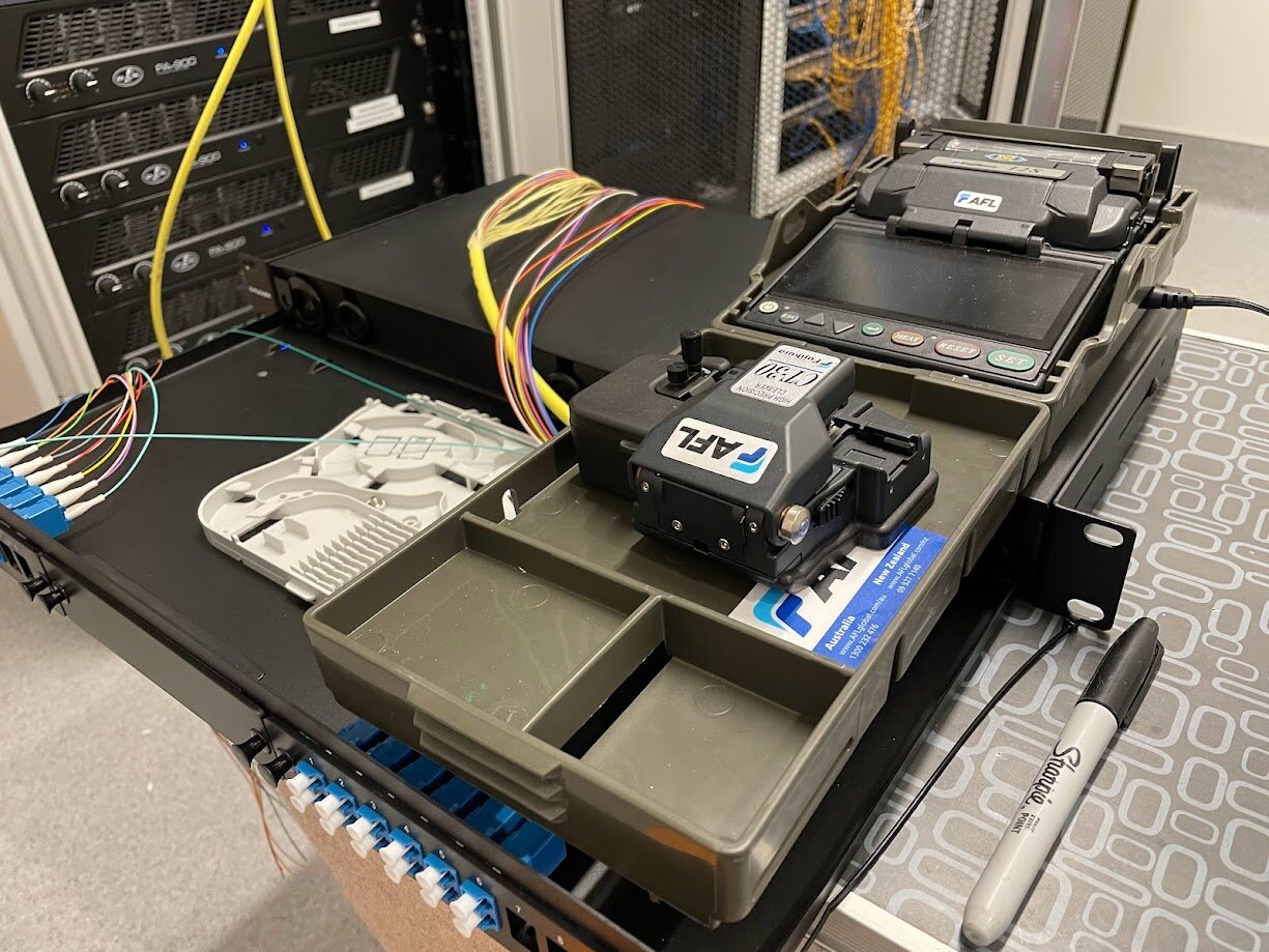 Fusion splicer at work beside an open fibre panel